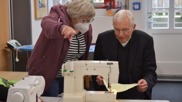 Weihbischof Dr. Nikolaus Schwerdtfeger näht unter Anleitung von Bärbel Schneegans einen Wimpel. Zum Godehardtag am 9. Juli 2022 in Duderstadt soll eine Wimpelkette die Straßen schmücken. | Foto: Johannes Broermann / cps Weihbischof Dr. Nikolaus Schwerdtfeger näht unter Anleitung von Bärbel Schneegans einen Wimpel. Zum Godehardtag am 9. Juli 2022 in Duderstadt soll eine Wimpelkette die Straßen schmücken. | Foto: Johannes Broermann / cps