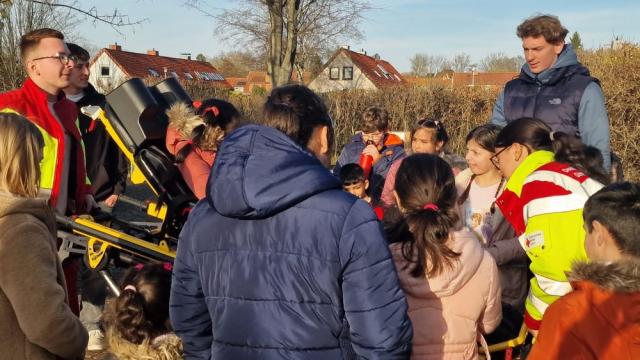 Die DRK-Sanis Valentin Busse und Carolina Kirscht erklärten ausführlich alles rund um die Funktionsweise der Trage aus dem Rettungswagen. | Foto: Caritas Die DRK-Sanis Valentin Busse und Carolina Kirscht erklärten ausführlich alles rund um die Funktionsweise der Trage aus dem Rettungswagen. | Foto: Caritas